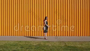 美丽的年轻女子穿着黑白相间的连衣裙站在一条街的中间，在阳光明媚的日子里玩弄着她的头发。
