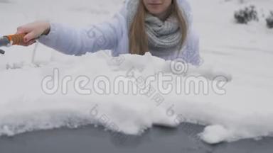 年轻漂亮的女孩用刷子<strong>擦车</strong>上的雪