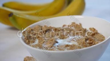 玉米片和牛奶放在碗里。 香蕉碎片落在这顿美味早餐的顶部。 特写镜头
