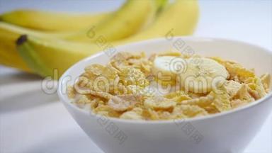 玉米片和牛奶放在碗里。 香蕉碎片落在这顿美味早餐的顶部。 特写镜头