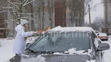年轻漂亮的女孩用刷子擦车上的雪