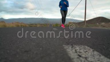 跑鞋-在山区的沙漠道路上系鞋带的女人。 慢动作