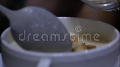 在一个碗里加奶酪汤，女孩<strong>用勺子</strong>搅拌汤。 慢动作