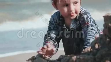 男孩年龄2岁，外表漂亮，在海边的沙滩上玩耍。 湿衣服和乐趣。 夏季一天