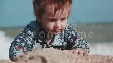 男孩年龄2岁，外表漂亮，在海边的沙滩上玩耍。 湿衣服和乐趣。 夏季一天