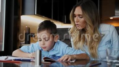 微笑的妈妈帮儿子做作业，口述课文，帮你写坐在厨房的桌子旁。
