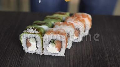 筷子的特写镜头将寿司卷在盘子或拼盘上。在日本酒吧餐厅提供。顶部