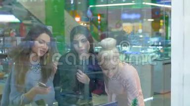 女士们站在<strong>商场</strong>的购物窗口旁，有<strong>感</strong>情地讨论购物。