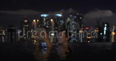 在吉隆坡一家酒店屋顶的游泳池里，马来西亚男子在平板电脑上<strong>观看视频</strong>并微笑