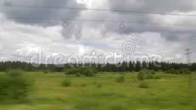从火车车窗上看到的景色。 夏日，云彩，绿树，电力线路，铁路过境