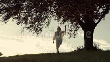 穿着boho外观的运动女孩<strong>跑到</strong>这棵不寻常的树触摸它，日落。