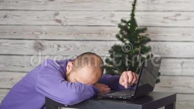 累了的年轻商人在除夕办公。 办公室里的圣诞树。 桌子上有笔记本电脑。 商业概念。 男子
