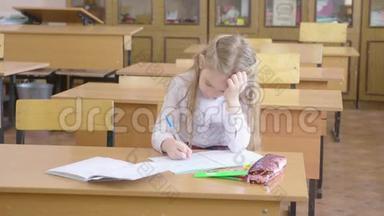 小女孩坐在学校的班级里学习。
