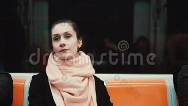 坐在地铁里的年轻体贴的女人的肖像。 女孩用<strong>公共交通工具</strong>，环顾四周，看着窗户。