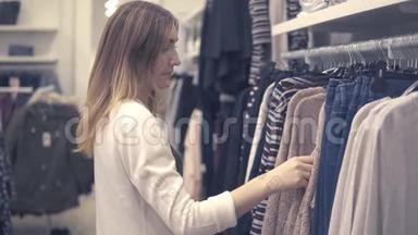 年轻的美女在时尚商场购物，挑选新衣服
