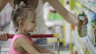 小姑娘带着可爱的女儿在杂货店挑酱