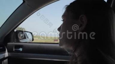 风吹过女孩的剪影和头发在车里。
