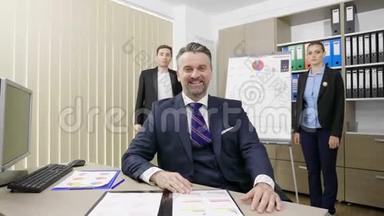 商人在繁忙的办公室里与两位同事在后台工作的画像