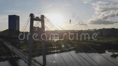 一个人走在一根绳子上，绳子在桥的支架之间在高空。