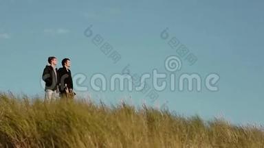 在大<strong>风天</strong>，两个年轻人站在高高的草地上朝同一个方向看