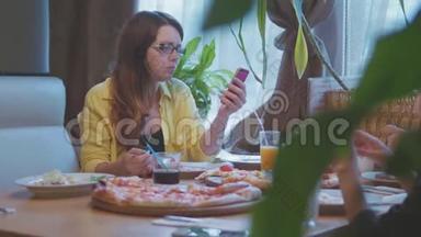 女孩在咖啡馆吃披萨，快餐，慢动作视频，保持智能手机社交媒体。 人们一起吃披萨