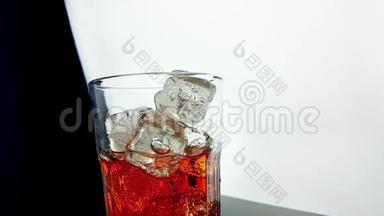将橙色饮料酒精鸡尾酒倒入杯中，杯中有黑色背景的冰块