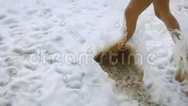 女人的特写镜头`美丽的晒黑的腿在沙滩上漫步，踏入大海。 波的图像