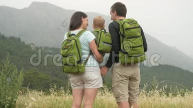 一个年轻的<strong>旅人</strong>家庭，带着一个回头看群山。 每个人都有相同的绿色背包。