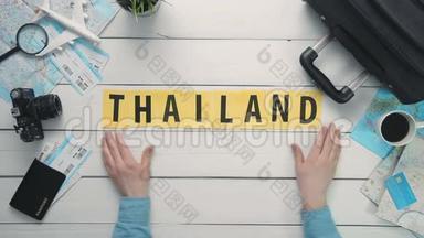 上观时间流逝的双手躺在白色的办公桌上`泰国，装饰着旅行用品