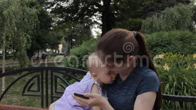 一个年轻的女人向一个抱着她的小女孩展示手机屏幕，小女孩把东西推到上面
