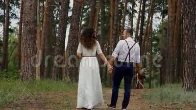 这对夫妇在一片松林里消磨时光。然后转身拥抱对方。在高大树木的背景下。