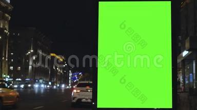 有绿色<strong>屏幕</strong>的广告牌，位于一条繁忙的街道上。 <strong>汽车</strong>在晚上移动。