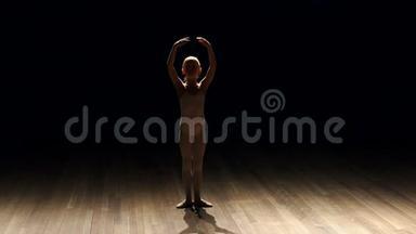 女芭蕾舞演员在黑暗中上台的剪影。
