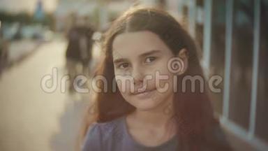 城市中一个小女孩的肖像，人群散步，人们慢动作视频。 女孩青少年的阳光肖像。 城市