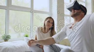 一对年轻可爱的夫妇，带着平板电脑和虚拟现实耳机，坐在床上<strong>玩</strong>360<strong>VR</strong>电子游戏