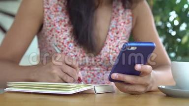 女人用手机和笔记<strong>本来</strong>学习英语。