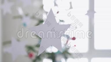 挂在窗户旁边一棵圣诞冷杉树前景的纸星星。圣诞节的概念。慢动作。3840x2160
