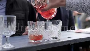 酒吧老板准备饮料，双手调酒师把鸡尾酒倒入装有冰块的玻璃杯中，酒吧老板把酒从玻璃杯中倒入