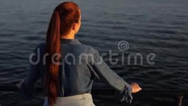 年轻美丽的白人中年妇女，红色头发，穿着蓝色<strong>牛仔裙</strong>，站在海边。