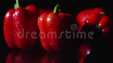 成熟的红辣椒在黑色背景上旋转。 特写，慢动作.. 一滴水从物体上流下来。