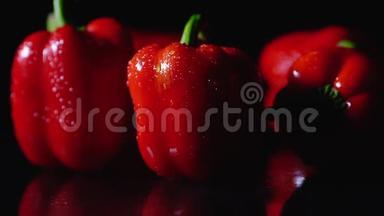 成熟的红辣椒在黑色背景上旋转。 特写，慢动作.. 一滴水从物体上流下来。