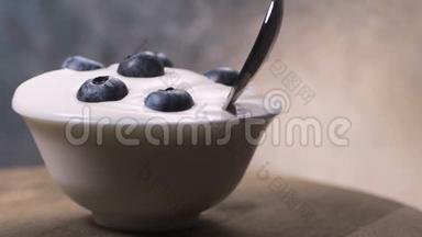 <strong>用勺子</strong>吃蓝莓和奶油或酸奶，水果背景。