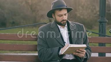在公园里坐在城市街头的长椅上，一个戴着帽子、穿着外套、拿着笔和素描的艺术家