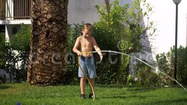 男孩在给<strong>草坪浇水</strong>时试图应付喷水