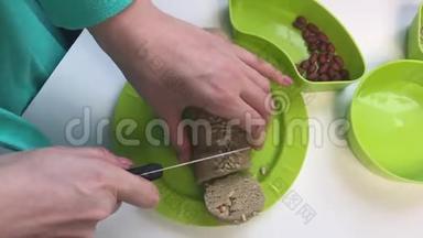 一个女人用<strong>碎花</strong>生、葵花籽和蜂蜜把香肠切成一部分。 哈尔娃，在家做饭。