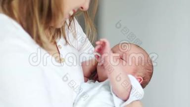一个新生婴儿在母亲的怀里睡着了。 在梦中挥动他的手。 妈妈和孩子。 母亲节