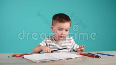 小男孩在桌子上用彩色铅笔画画。