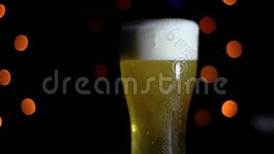 酒吧里有一杯黑色<strong>背景</strong>上的冷啤酒，上面有<strong>彩灯</strong>。 啤酒在玻璃杯里起泡。 高清高清