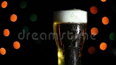 黑色背景上的一杯冷啤酒，有彩灯。 水滴顺着玻璃流下来。 假日的心情