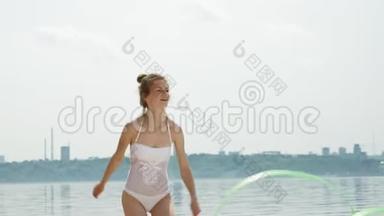 年轻女子穿着白色的身体在沙滩上用体<strong>操</strong>丝带<strong>跳</strong>舞。 夏天，黎明